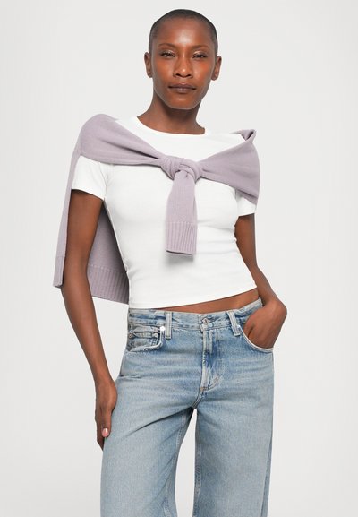 White fitted t-shirt paired with light blue high-waisted jeans. A soft lavender sweater tied around the shoulders. Smooth fabric, casual style.