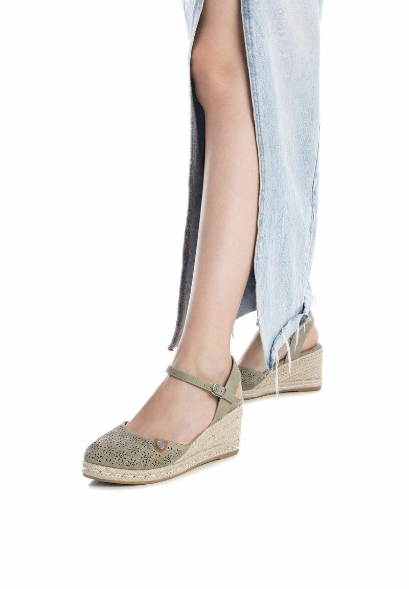 Sandali wedge beige con motivo a intaglio, cinturino alla caviglia e dettagli in juta intrecciata sulla suola. Abbinati a una gonna di jeans azzurro chiaro.