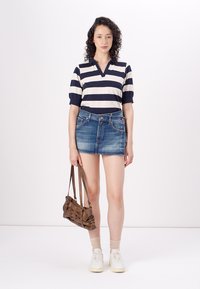 Marineblå og hvite stripete kortermet polo skjorte, kombinert med en denim mini skjørt. Looket fullføres med hvite sneakers og en brun håndveske.
