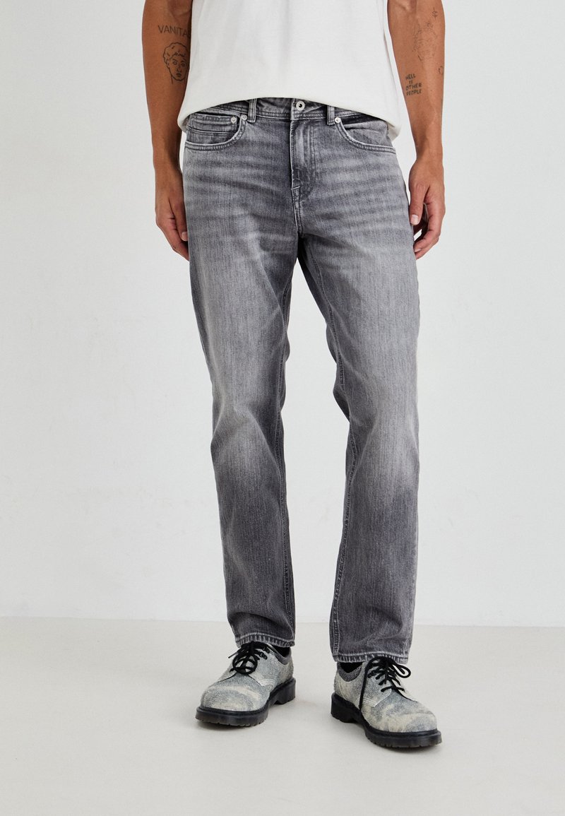 Γκρι τζιν παντελόνι με ίσια γραμμή, ξεθωριασμένη απόχρωση, πέντε τσέπες και αντίθετες ραφές, συνδυασμένο με γκρι κορδονάτα παπούτσια.