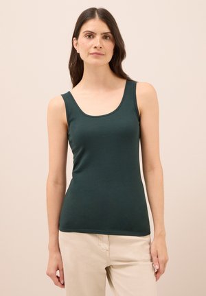 Grünes Tanktop aus weichem, dehnbarem Stoff mit Rundhalsausschnitt und breiten Trägern, kombiniert mit hellen Hosen. Glatte Textur und taillierte Passform.