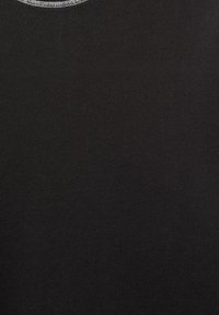 Gros plan d'un tissu noir montrant un tissage finement texturé avec une couture blanche contrastante le long du bord supérieur.