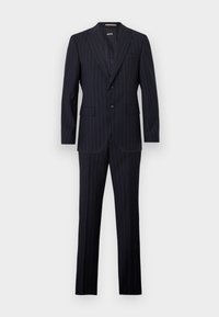 Costume deux pièces bleu marine foncé à fines rayures avec une veste à revers cranté et un pantalon droit assorti sur fond blanc.