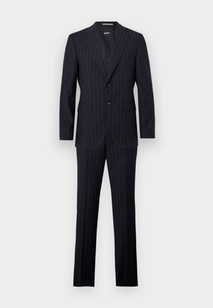 Donker marineblauw kostuum met krijtstreep, bestaande uit een colbert met inkeping aan de revers en bijpassende rechtvallende broek, tegen een witte achtergrond.