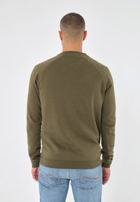 Sudadera verde oliva de manga larga, con puños acanalados y cuello redondo. El material parece suave con una textura lisa.