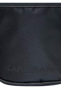 Crna platnena torba s teksturiranom površinom, urezanim logotipom "KARL KANI", zaobljenim rubovima i uskim dizajnom. Izdržljiva završna obrada.
