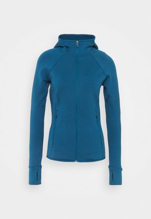 Turkusowa bluza z kapturem na zamek, dopasowanego kroju, z rękawami raglanowymi i bocznymi kieszeniami. Zawiera otwory na kciuki w mankietach dla dodatkowego komfortu. Miękka faktura.