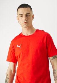 Rode katoenen t-shirt met een ronde hals en korte mouwen, voorzien van een wit Puma-logo op de linkerkant van de borst. Gladde textuur.