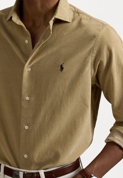 Kaki kordfløyelskjorte med knappestolpe, som har en liten brodert logo. Strukturert stoff med en jevn, formet passform.
