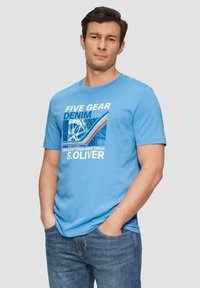 Lichtblauwe katoenen t-shirt met korte mouwen, voorzien van een grafische print met tekst en kleuren in wit en blauw, gecombineerd met denim jeans.