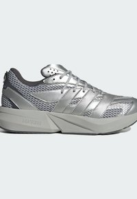 Stříbrná sportovní obuv s textilním síťovým materiálem a kovovými akcenty. Obsahuje polstrovanou, úhlovou podrážku označenou "LIGHTSTRIKE" pro podporu.
