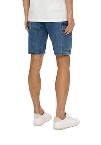 Denim shorts in medium blue, met een relaxte pasvorm, opgerolde zoom en zijzakken. Draagt het met witte sneakers.