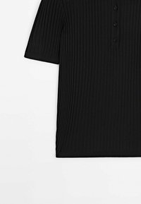 Chemise noire côtelée à manches courtes avec une patte de boutonnage comportant quatre boutons noirs, présentée sur un fond blanc.