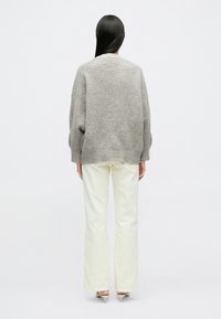 Helehall halli palmikutega kampsun tekstuurse mustriga ja soonikkoes äärtega, serveeritud koos kreemjate laiade pükstega ja beežide kontsaga kingadega.