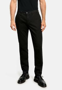 Zwarte chino's met een rechte snit, van een katoenmix, met knoop- en ritssluiting en voorzakken, gecombineerd met zwarte leren schoenen.
