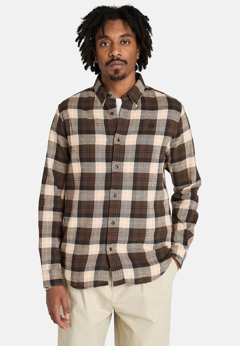 Camisa de franela a cuadros marrón y crema con diseño de botones, que cuenta con un cuello, mangas largas y un corte relajado. Textura suave.