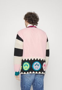 Gebreide trui met strepen in roze, zwart en crème, voorzien van een kleurrijke afbeelding op de onderste zoom. Gestructureerde stof met geribbelde manchetten.