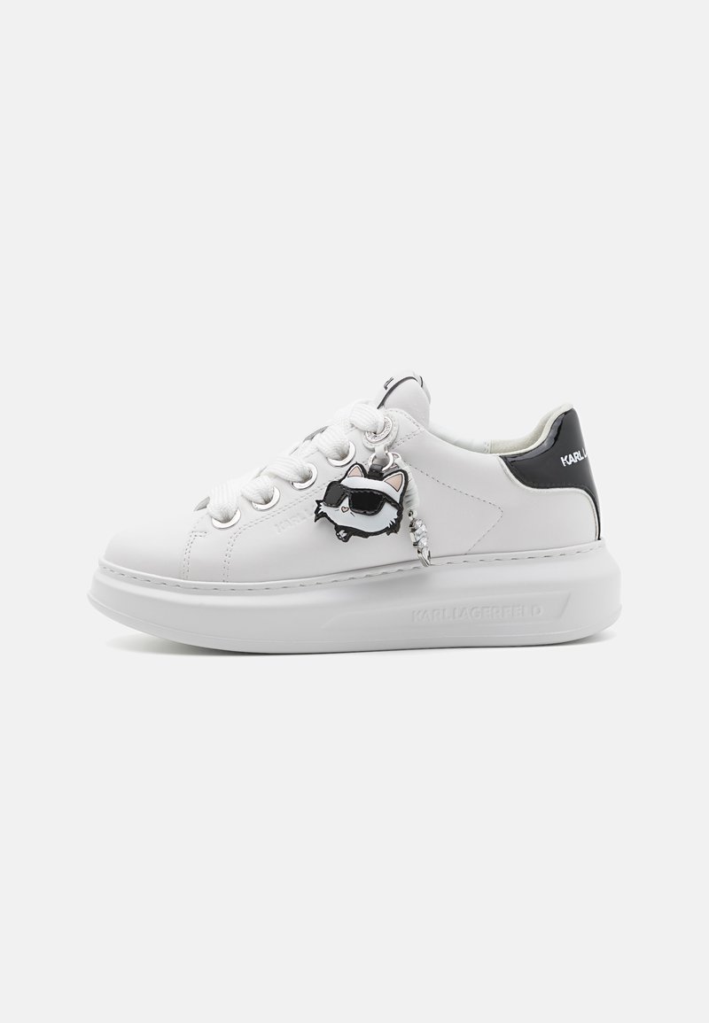 Adidași din piele albă cu o talpă groasă, prezentând accente negre și un charm cu un personaj de raton. Găuri rotunde pentru șireturi și detalii cusute.