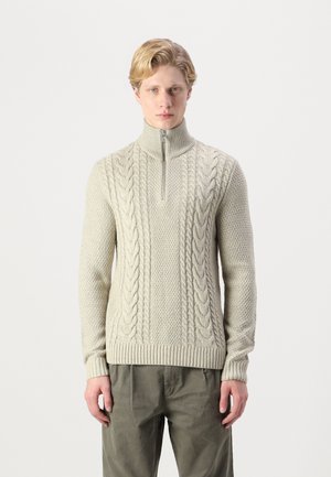 Suéter de punto gris claro con un cuello alto y media cremallera, que presenta un patrón de trenzado texturizado y puños y dobladillo acanalados.