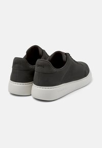 Schwarze Leder-Sneaker für Herren mit einer weißen Gummisohle, runder Form, Schnürdesign, glatter Textur und eingeprägtem Logo an der Ferse.