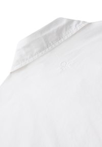 Camicia bianca in cotone con colletto classico e discreto dettaglio di logo ricamato vicino alla spalla.