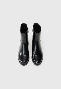 Stivaletti neri in pelle con una texture liscia, punta rotonda e zip laterali. Il design presenta una silhouette minimalista e slanciata.