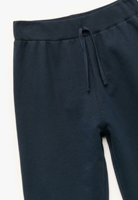 Mørkeblå joggingbukser med ribbet talje, snøre og et blødt, tekstureret stof. Designet inkluderer lige ben og ingen synlige mønstre.