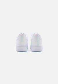Sneaker bianche con finitura in pelle liscia, design low-top, punta rotonda e suola in gomma. Presentano un sottile accento rosso sul tallone.