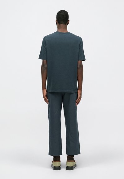 Dunkelblaues Baumwoll-T-Shirt, kombiniert mit passenden, locker sitzenden Hosen. Einfaches Design mit Rundhalsausschnitt und geradem Bein.