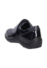 Scarpa in pelle verniciata nera con cinturino in Velcro, caratterizzata da una punta arrotondata, superficie testurizzata e suola esterna in gomma flessibile.