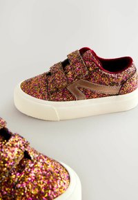 Sneaker rosa e dorati brillanti con interno in velluto, suola in gomma bianca e due cinturini in velcro per una facile vestibilità. Texture scintillante su tutta la superficie.