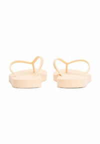 Ferskenfarvede flip-flops med tykke såler, struktureret fodseng og tynde stropper, der danner en hjerteform. Glat, fleksibelt materiale med minimal detalje.
