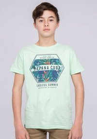 T-shirt vert menthe arborant un graphique hexagonal avec des feuilles tropicales et le texte "HAVANE CUBA" et "ÉTÉ SANS FIN" dans des couleurs sombres.
