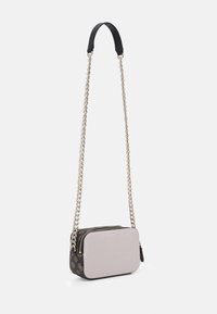 Kabelka přes rameno s řetízkem, která má jemně růžový přední díl, černé vzorované strany a zlaté kovové detaily se zipovým uzávěrem.