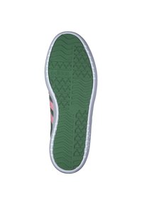 Zeleni gumeni đon tenisica s bijelim rubovima, s teksturiranim uzorkom i istaknutim Adidas logotipom. Ružičaste naglasne pruge sa strane.