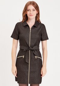Robe zippée noire à manches courtes, avec une ceinture à la taille et deux poches zippées à l'avant. Présente un motif texturé avec des accents dorés.