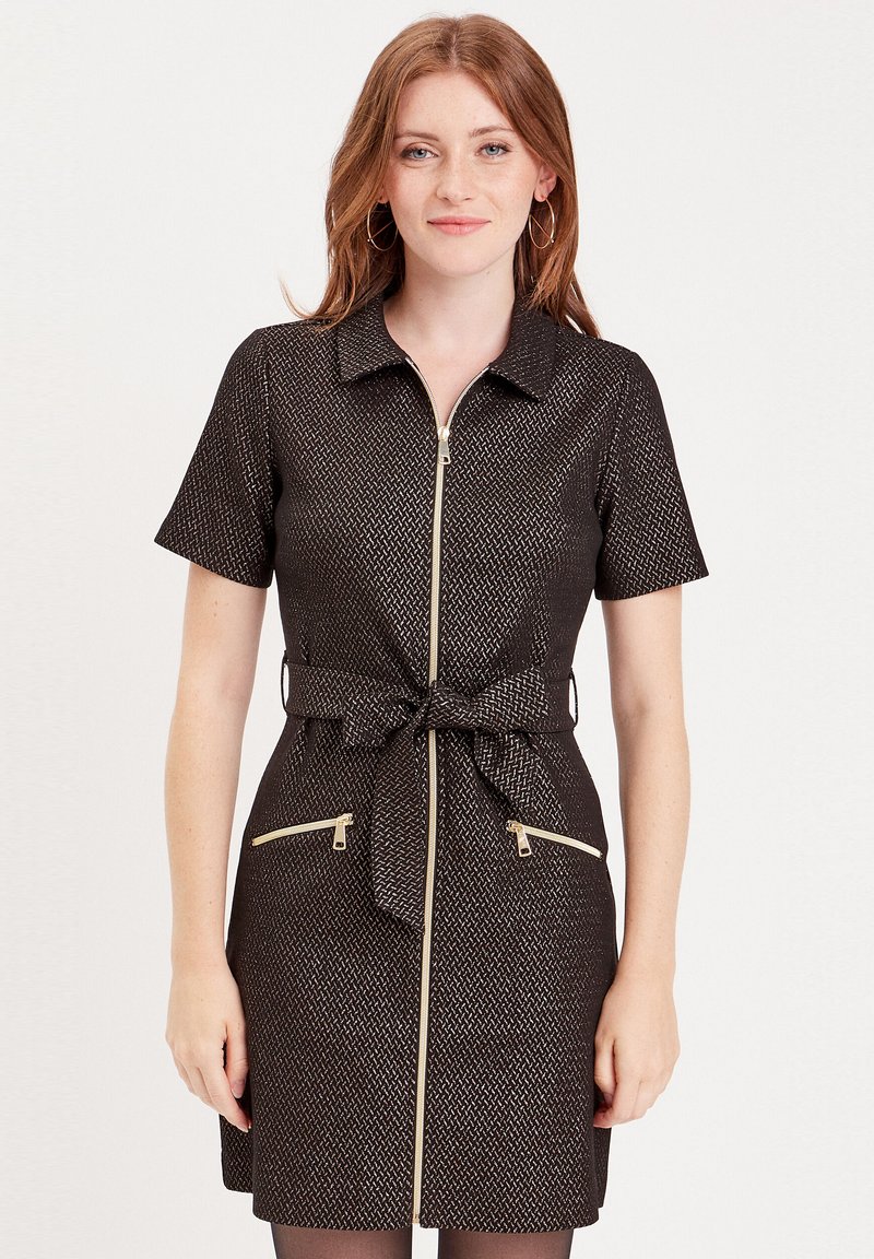 Robe zippée noire à manches courtes, avec une ceinture à la taille et deux poches zippées à l'avant. Présente un motif texturé avec des accents dorés.