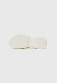 Suola di scarpa in gomma di colore bianco sporco, con motivi texturizzati per una presa sicura e bordi curvi. Design piatto senza marchi o dettagli visibili.