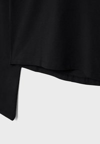 Čierne bavlnené tričko s rovným strihom a mierne predĺženým zadným dielom, s hladkou textúrou. Minimalistický dizajn bez ďalších vzorov.