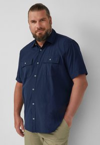 Marineblauwe short-sleeve shirt met een button-down kraag, twee borstzakken en lichtblauwe knopen. Heeft een gestructureerde stof.
