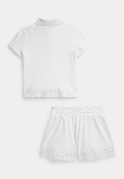 Λευκό δίκομψο σύνολο με κοντομάνικο πόλο τοπ με διακοσμητικό περίγραμμα από κοφτό κέντημα και ταιριαστό σορτς με ελαστική μέση και τελείωμα από κοφτό κέντημα.