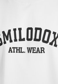 Weißes Baumwoll-Sweatshirt mit kräftigem schwarzen Text: "SMILODOX ATHL. WEAR." Klassisches Rundhalsausschnitt-Design mit weichem Stoff.