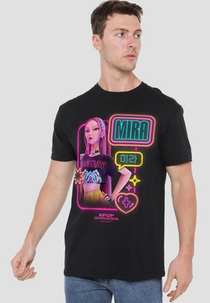 Man wearing black t-shirt featuring neon-style graphic of a female character named Mira from K-Pop Demon Hunters, with bright pink, teal, and yellow colors.