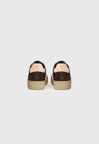 Brune semskede sko med lyserøde teksturerede accenter på hælen, med en beige gummisål og en glat finish.