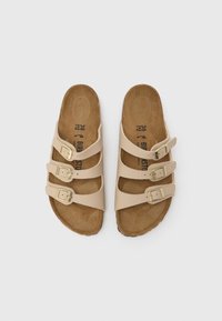 Μπεζ σανδάλια με τρεις ρυθμιζόμενες λουριά με αγκράφες, κατασκευασμένα από συνθετικό υλικό, με υφασμένο πάτο και καφέ σόλα.