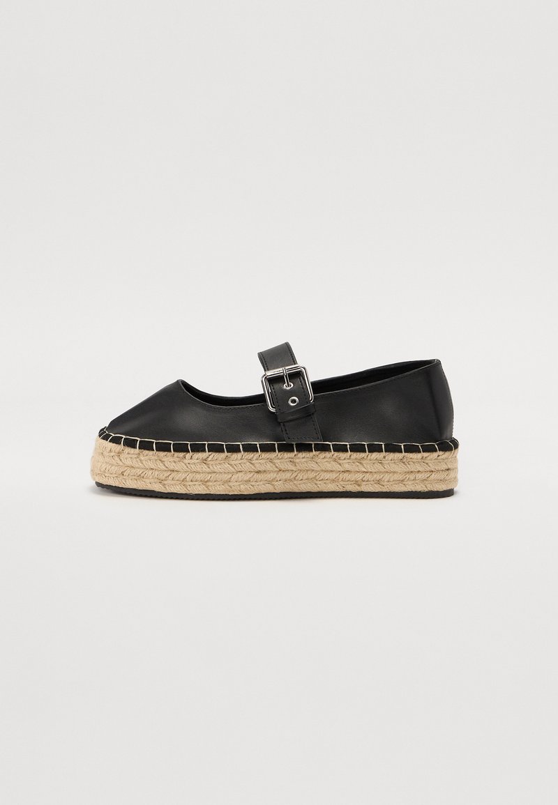 Espadrille en cuir noir avec un bout rond, une sangle à boucle et une semelle en jute tissée. Texture lisse et détails de couture contrastés.