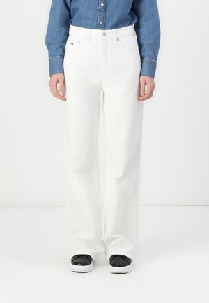 Hvide brede jeans lavet af denim, med høj talje, forlommer og et klassisk fem-lommer design. Sammen med sorte sneakers.