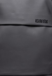 Hallitatud hall tekstuuriga kangas, millel on väikeste lohkudega muster. Ülemises osas on must "BIG STAR" logo.