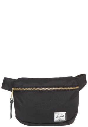 Banane en tissu noir avec une fermeture éclair dorée et une sangle ajustable, avec un petit écusson blanc de la marque Herschel en bas à droite à l'avant.