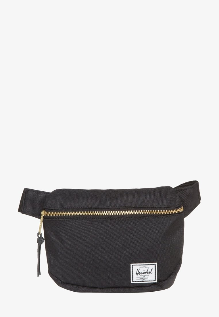Banane en tissu noir avec une fermeture éclair dorée et une sangle ajustable, avec un petit écusson blanc de la marque Herschel en bas à droite à l'avant.